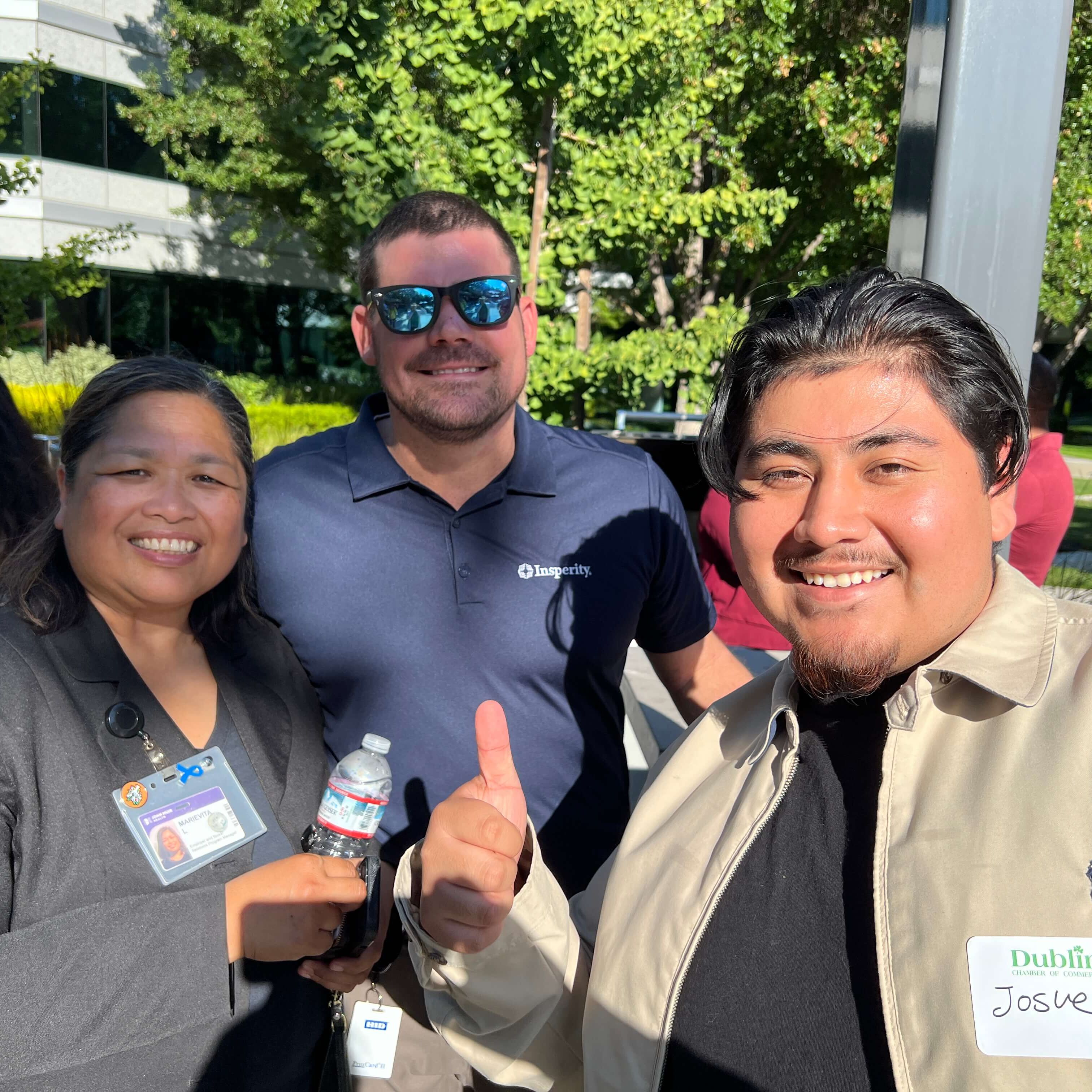 Group smailing at an outside event in the sunshine.